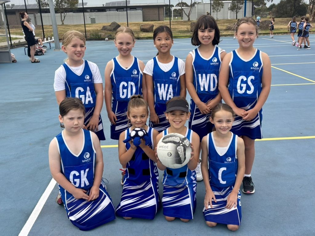 A young Bayside team kneeling with the match ball